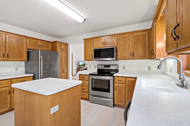 kitchen featuring brown cabinets, light tile patterned flooring, appliances with stainless steel finishes, a sink, and light countertops