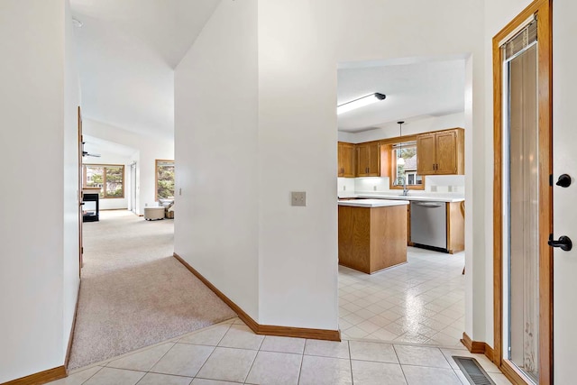 hallway featuring a sink, baseboards, light tile patterned flooring, and a wealth of natural light