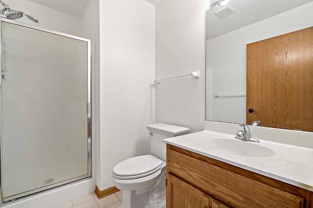 bathroom with toilet, a shower stall, tile patterned flooring, and vanity