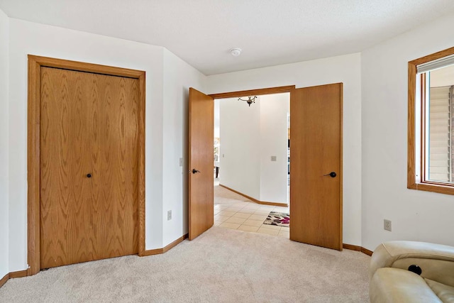 bedroom with baseboards, light colored carpet, light tile patterned floors, and a closet