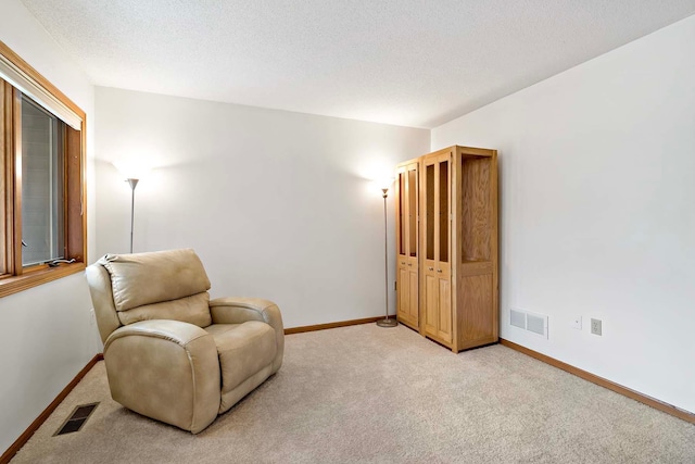 sitting room featuring baseboards, light carpet, and visible vents