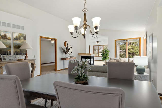 carpeted dining space featuring visible vents, lofted ceiling, and ceiling fan with notable chandelier