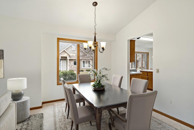 dining space featuring plenty of natural light, baseboards, a notable chandelier, and vaulted ceiling