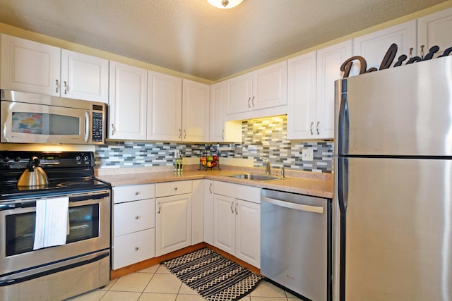 kitchen with sink, white cabinetry, tasteful backsplash, light tile patterned floors, and appliances with stainless steel finishes