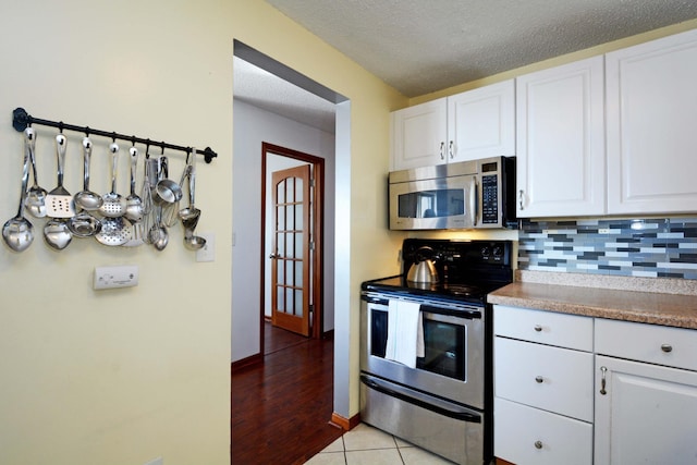 kitchen with white cabinetry, light tile patterned floors, a textured ceiling, and appliances with stainless steel finishes