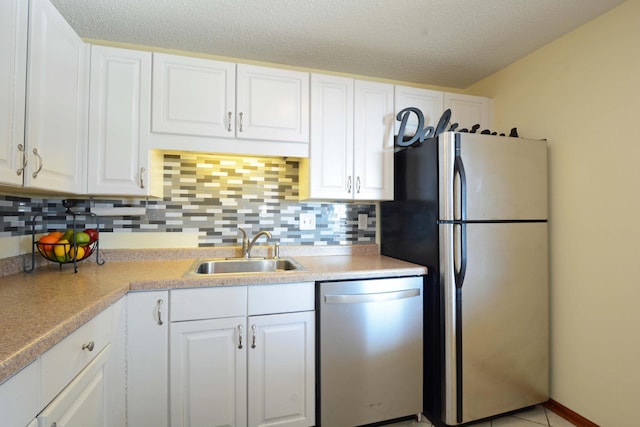 kitchen with sink, white cabinets, backsplash, stainless steel appliances, and a textured ceiling