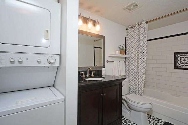 bathroom with visible vents, toilet, a textured ceiling, vanity, and stacked washing maching and dryer