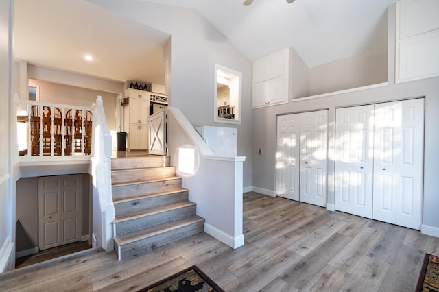 staircase featuring hardwood / wood-style flooring, ceiling fan, and lofted ceiling