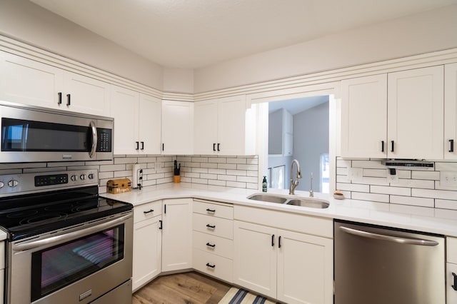 kitchen featuring appliances with stainless steel finishes, sink, decorative backsplash, and white cabinets