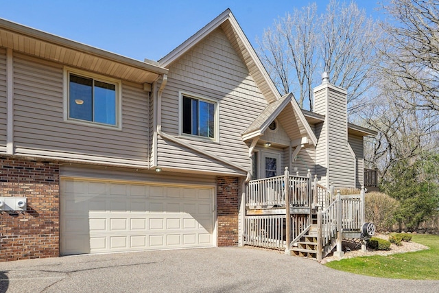 view of front facade featuring brick siding, aphalt driveway, a chimney, and a garage