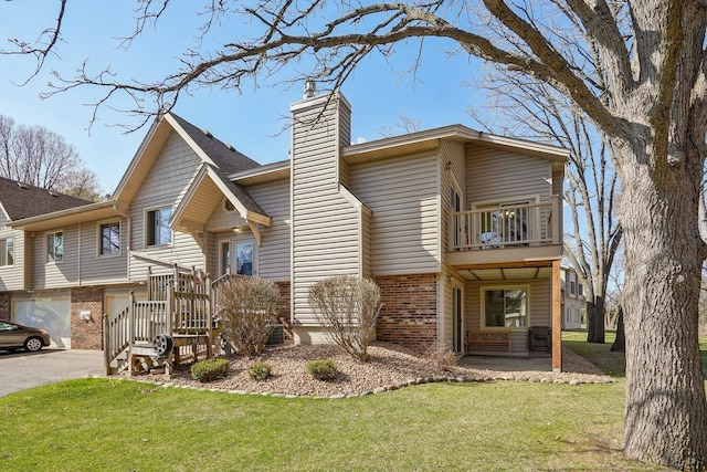 view of front facade with a chimney, aphalt driveway, a balcony, a front yard, and a garage