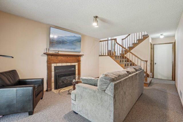 living room with carpet flooring, stairs, a textured ceiling, and a fireplace
