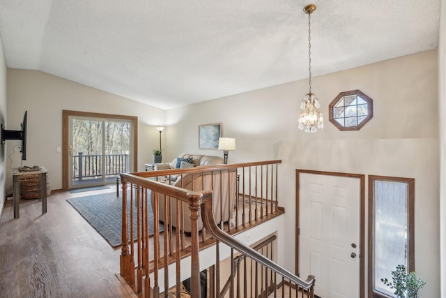 foyer entrance featuring vaulted ceiling, a notable chandelier, wood finished floors, and a textured ceiling