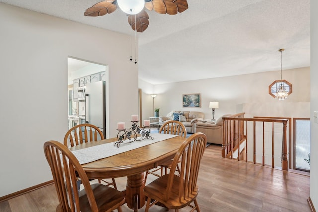 dining space featuring light wood-style floors and ceiling fan with notable chandelier