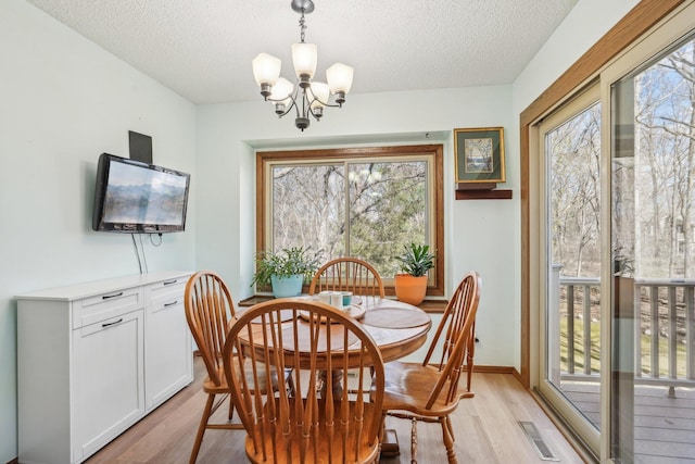 dining area featuring light wood finished floors, a chandelier, visible vents, and a textured ceiling