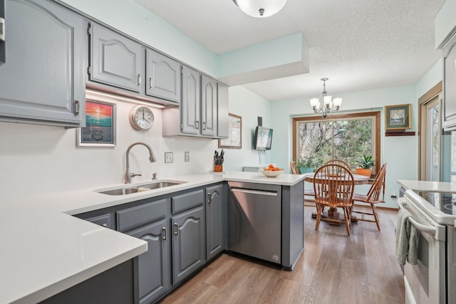 kitchen featuring a peninsula, a sink, light wood-type flooring, gray cabinetry, and dishwasher