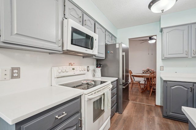 kitchen featuring a ceiling fan, white appliances, light countertops, dark wood finished floors, and gray cabinetry