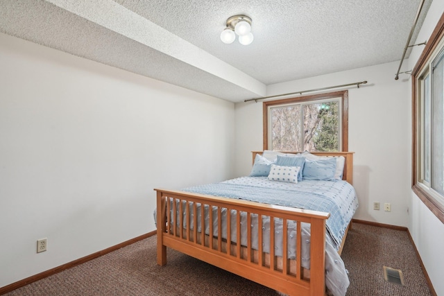 carpeted bedroom featuring a textured ceiling, visible vents, and baseboards