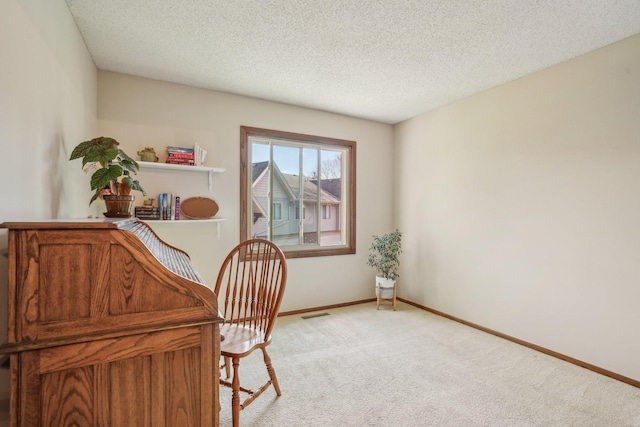 home office with light colored carpet, baseboards, a textured ceiling, and visible vents