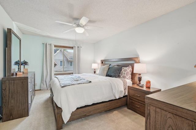 bedroom with a ceiling fan, a textured ceiling, and light colored carpet