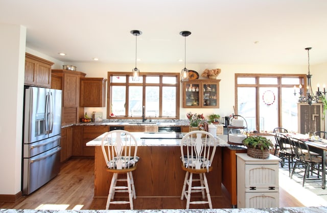 kitchen with brown cabinets, a breakfast bar, a sink, stainless steel fridge, and light wood finished floors