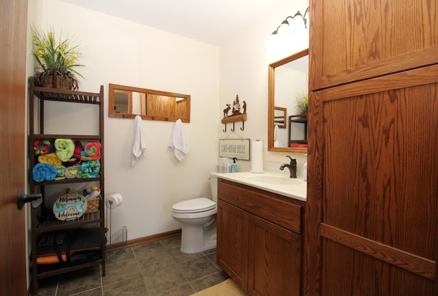 bathroom with toilet, vanity, and baseboards