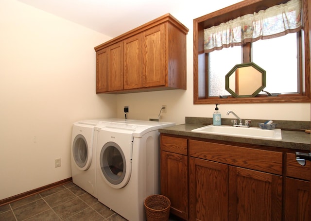 washroom with dark tile patterned floors, a sink, washer and dryer, cabinet space, and baseboards