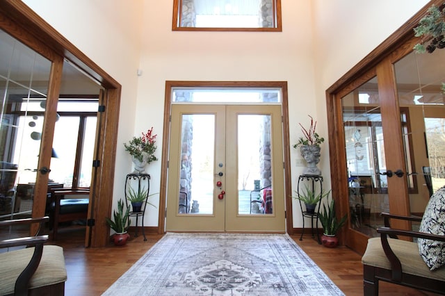 foyer entrance featuring french doors, plenty of natural light, wood finished floors, and a high ceiling
