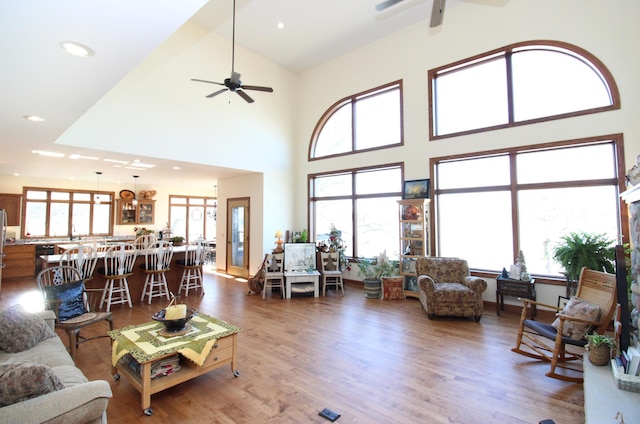 living room with ceiling fan, wood finished floors, a high ceiling, and recessed lighting