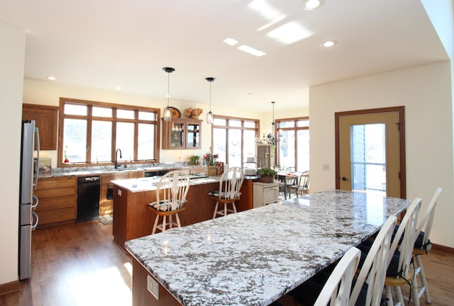 kitchen with a spacious island, brown cabinetry, freestanding refrigerator, a kitchen breakfast bar, and recessed lighting