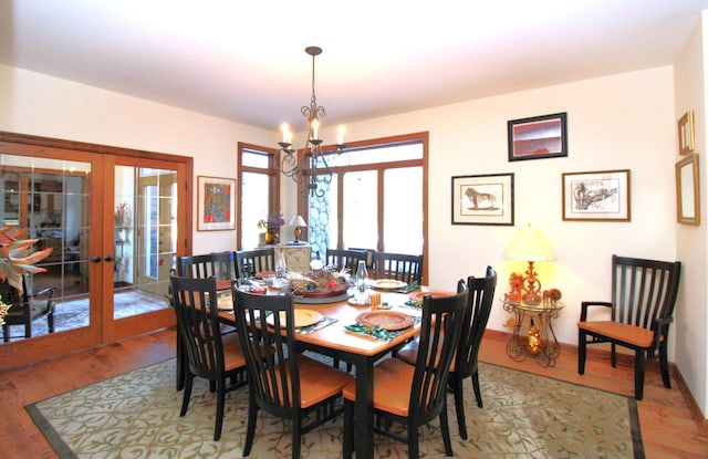 dining area with french doors, a chandelier, wood finished floors, and baseboards