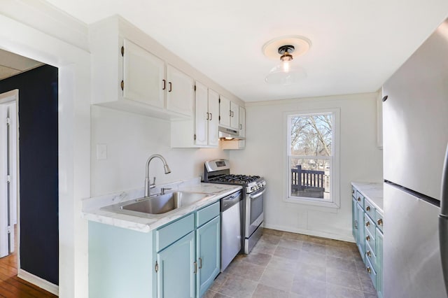 kitchen featuring stainless steel appliances, white cabinetry, sink, and blue cabinetry