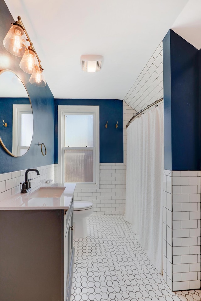 bathroom with tile walls, tile patterned flooring, vanity, walk in shower, and toilet