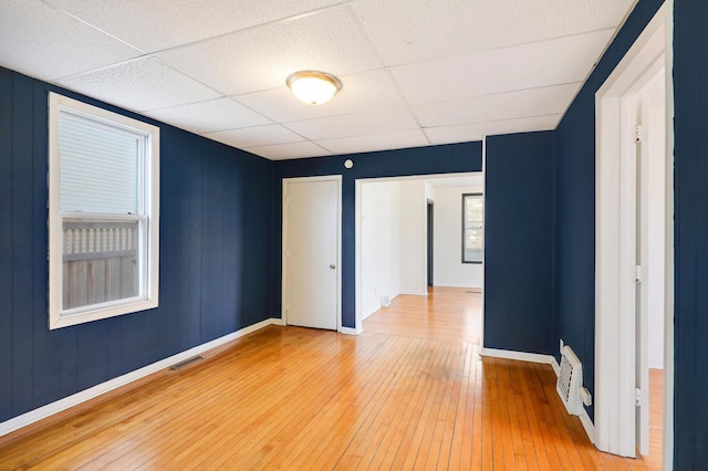 spare room with a drop ceiling and hardwood / wood-style floors