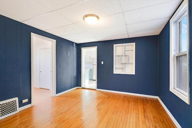 empty room with wood-type flooring and a paneled ceiling