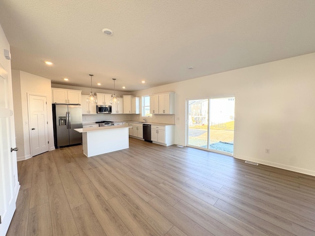 kitchen featuring appliances with stainless steel finishes, a center island, pendant lighting, and white cabinets