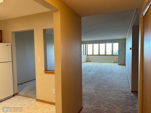 corridor featuring a baseboard heating unit and light colored carpet