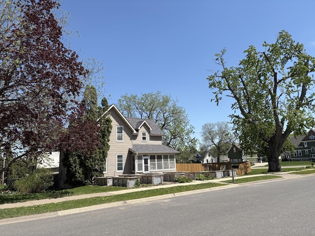 20 1st Ave NW, Plainview, MN 55964 - view of front of home with a sunroom, central AC unit, fence, and roof with shingles