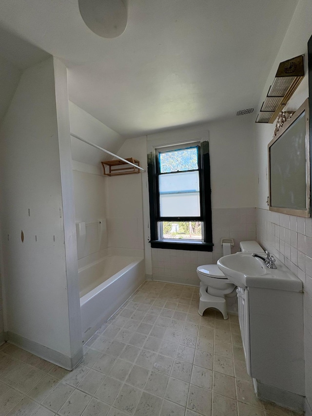 20 1st Ave NW, Plainview, MN 55964 - full bath with toilet, tile walls, vanity, vaulted ceiling, and shower / washtub combination