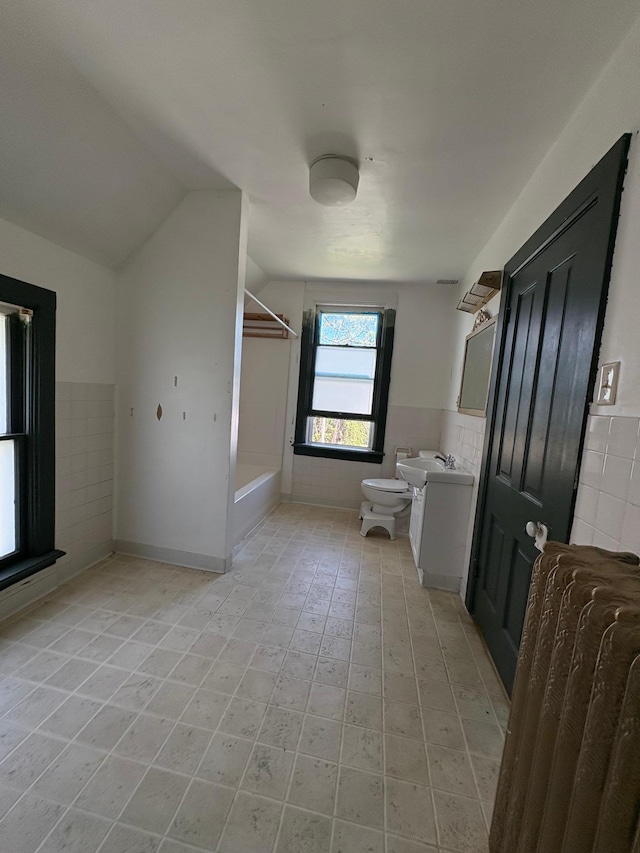 20 1st Ave NW, Plainview, MN 55964 - full bath featuring tile walls, lofted ceiling, bathtub / shower combination, toilet, and vanity
