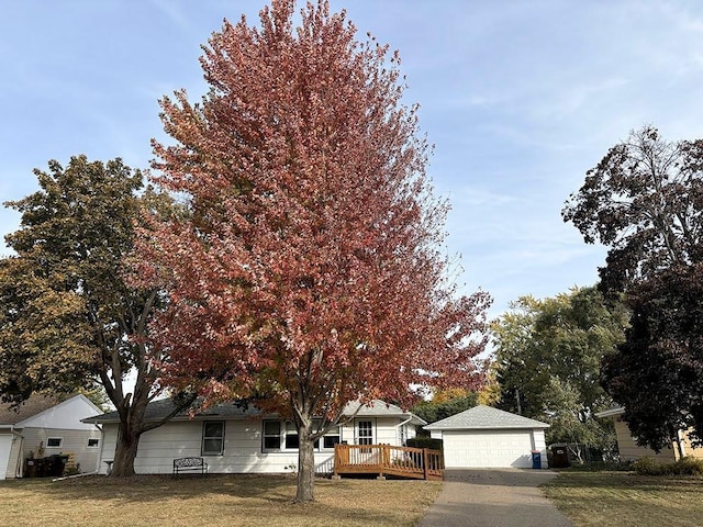 obstructed view of property with a garage, a wooden deck, and a front lawn