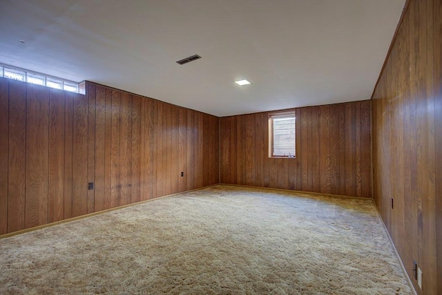 carpeted spare room with wood walls