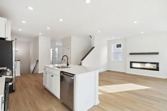 kitchen featuring sink, stainless steel appliances, an island with sink, and white cabinets