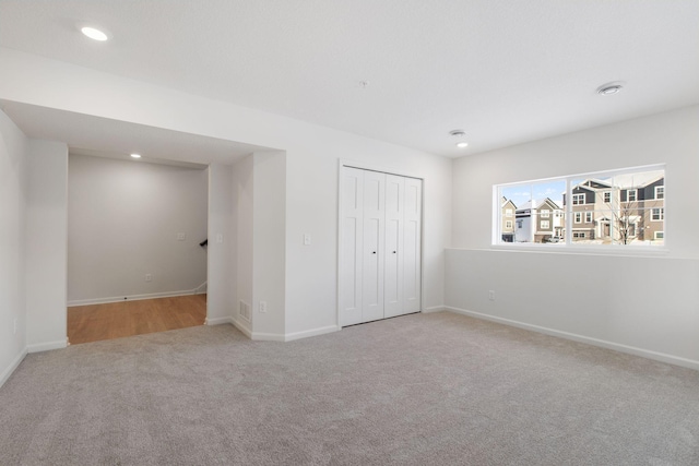 unfurnished bedroom with light colored carpet and a closet