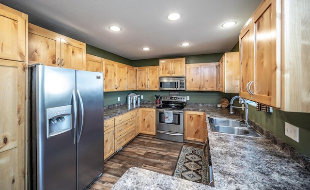 kitchen featuring dark hardwood / wood-style floors, light brown cabinetry, sink, dark stone counters, and stainless steel appliances