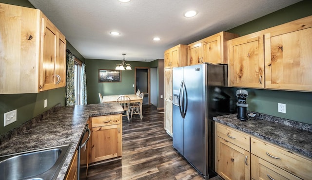 kitchen with pendant lighting, stainless steel appliances, dark wood-type flooring, light brown cabinets, and a textured ceiling