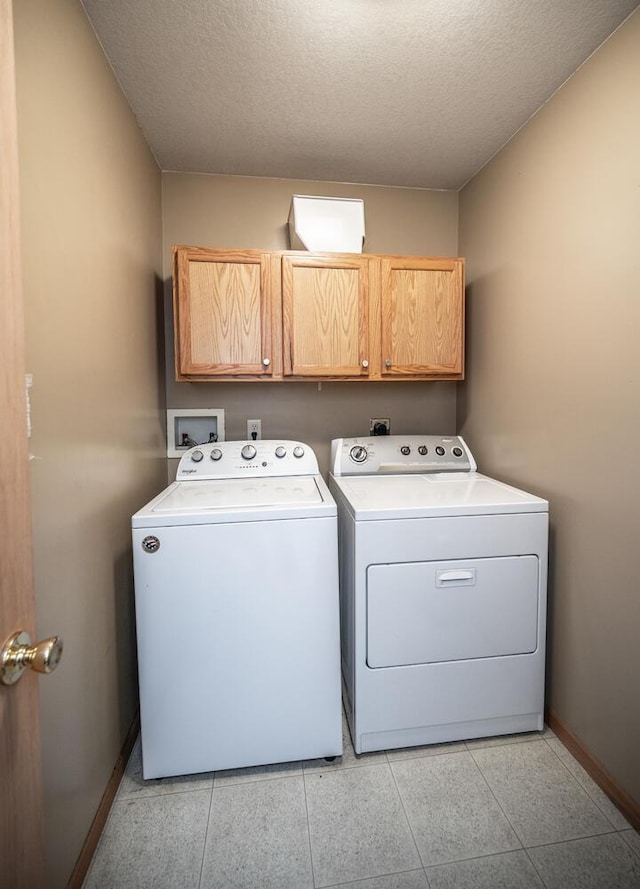 laundry area featuring cabinets, separate washer and dryer, light tile patterned floors, and a textured ceiling