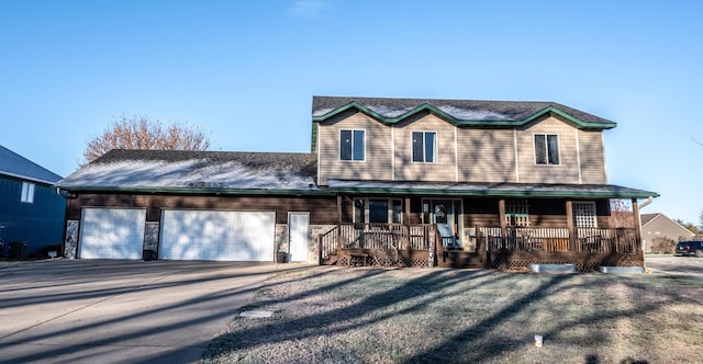 view of front of home with a garage, covered porch, and a front lawn