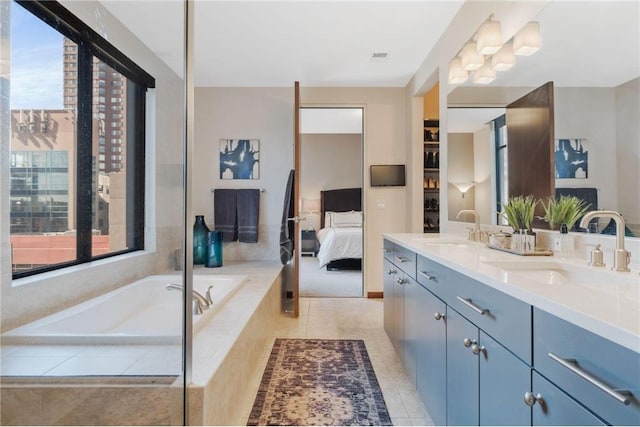 bathroom with tiled tub, vanity, and tile patterned flooring