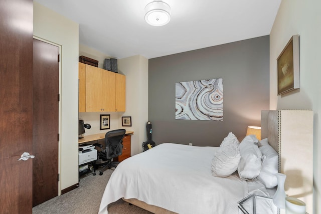 carpeted bedroom featuring built in desk